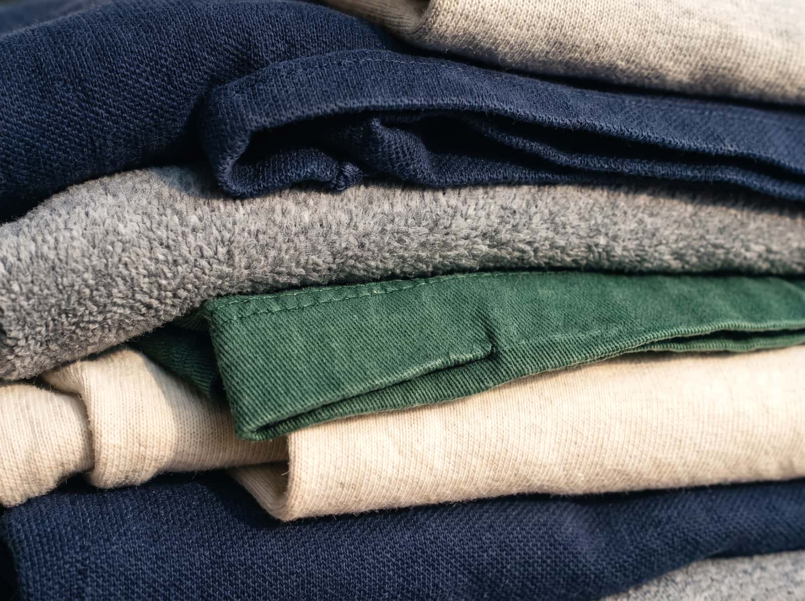 Close detail of stacked folded garments showing fabric weave and colour.