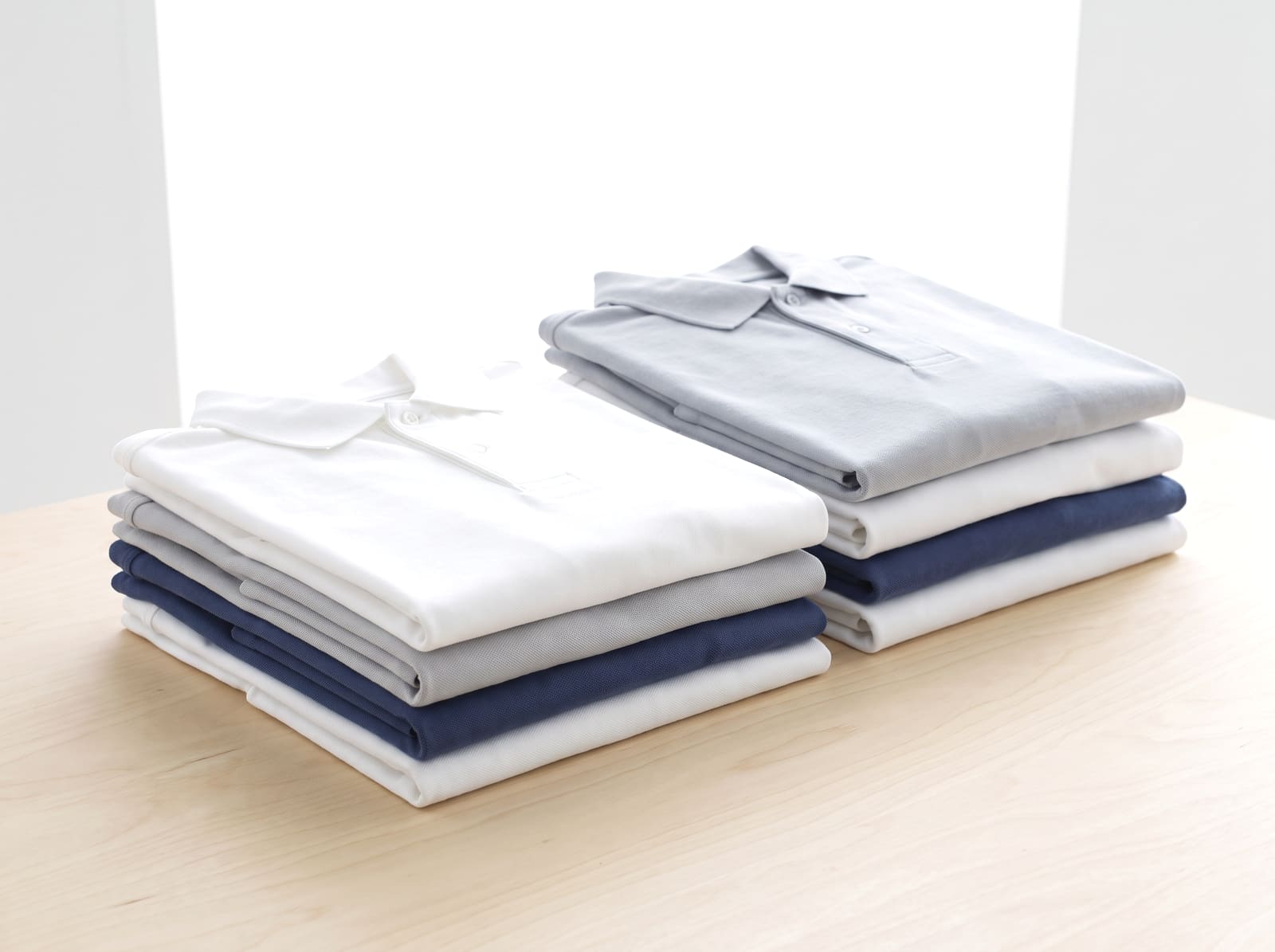 Stacks of folded blank polo shirts and work shirts.