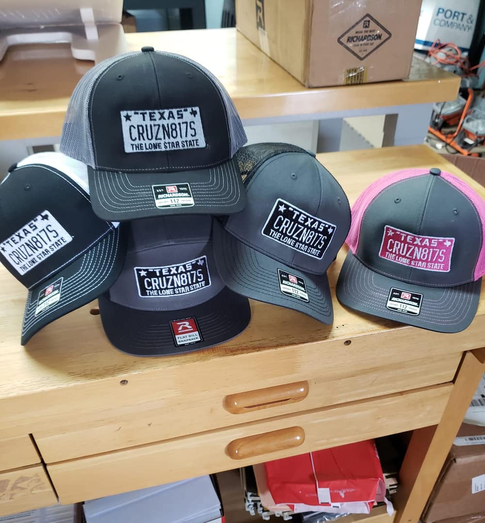 A pile of embroidered baseball caps in assorted colours.